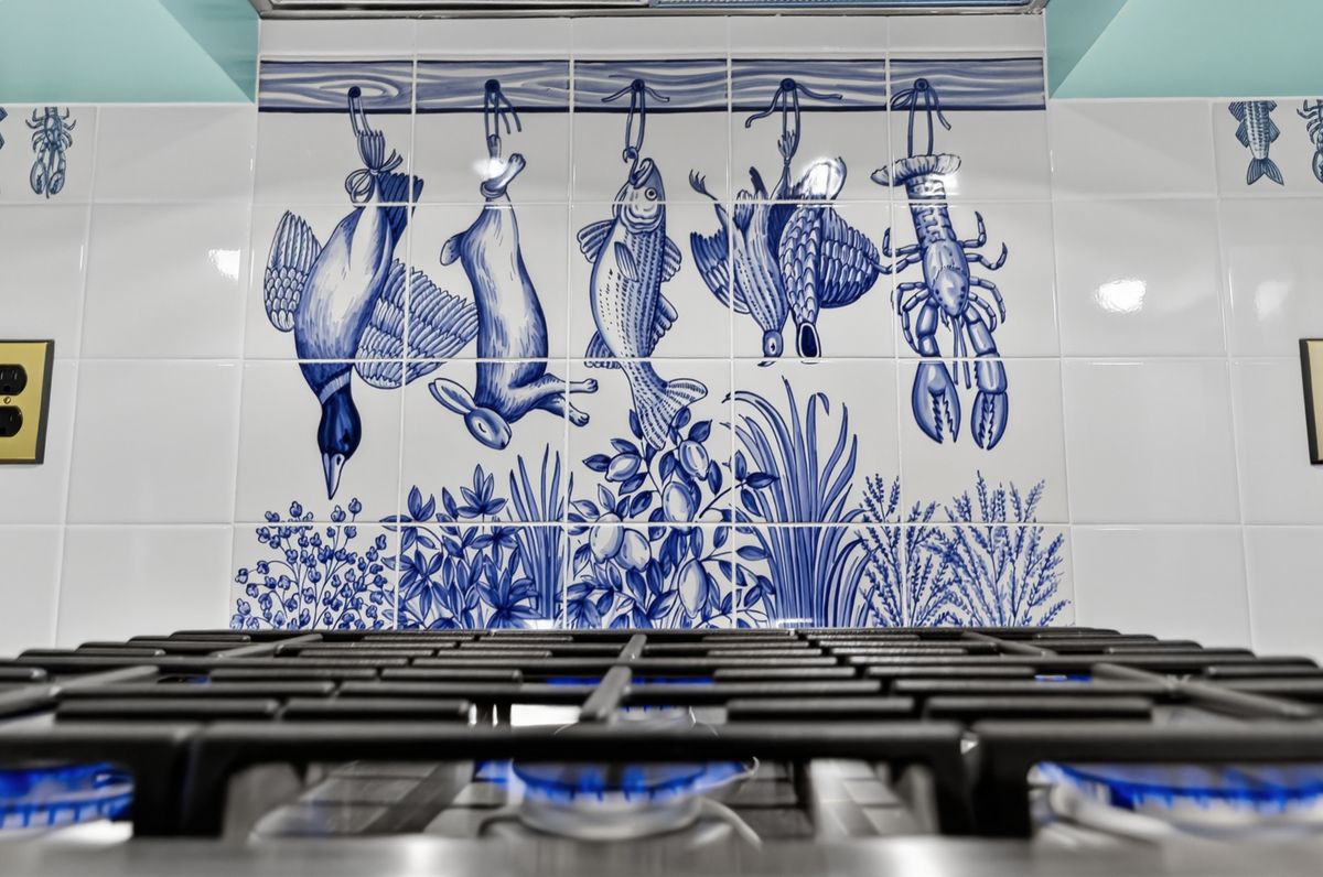 Hand-painted blue and white tile mural behind the range