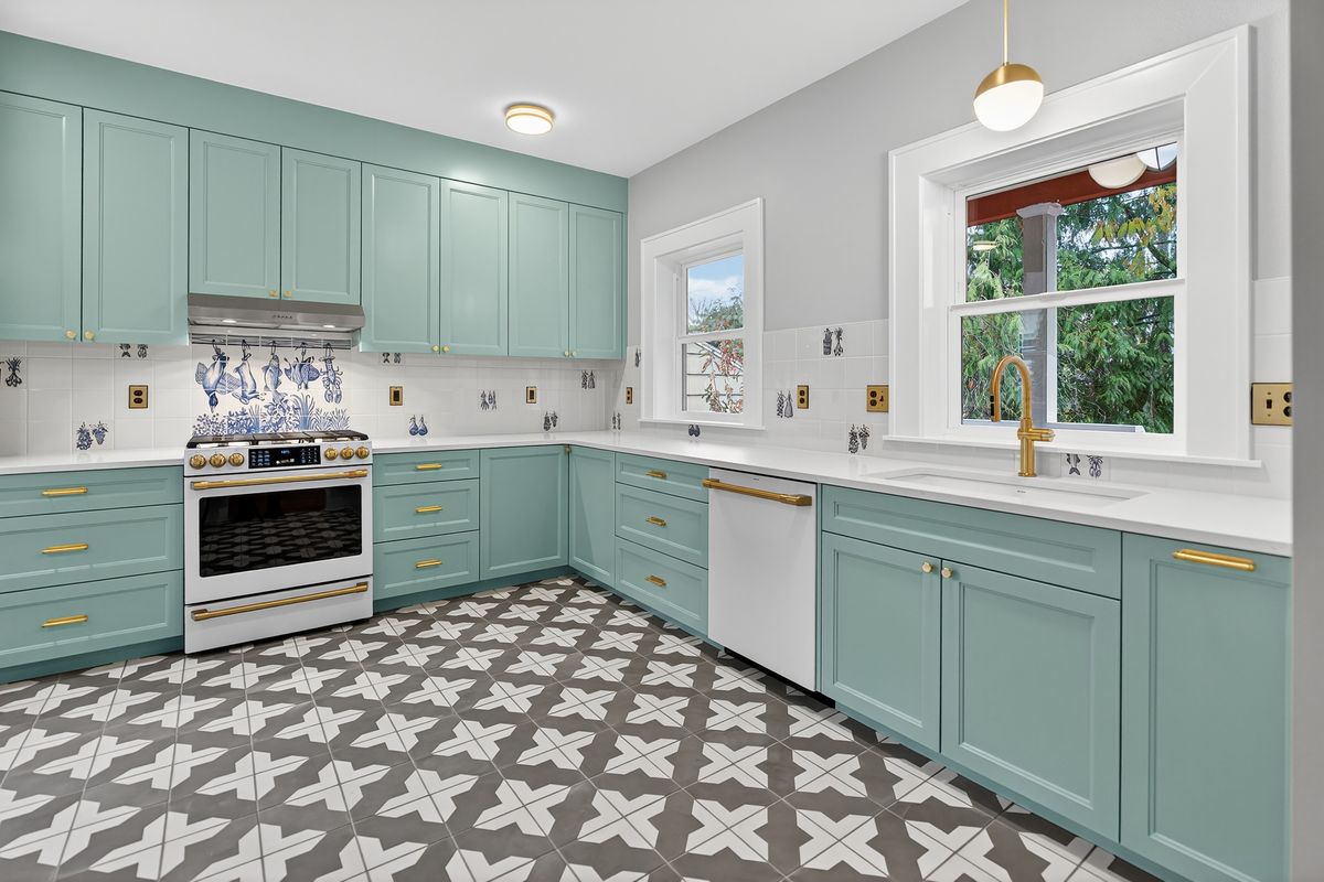 Main-house kitchen with sage-green painted cabinets, brass hardware and hand-painted tile backsplash