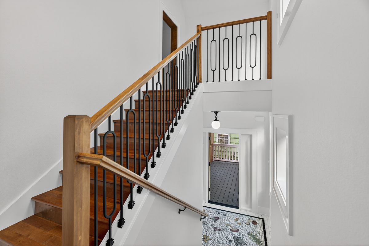 Alder stair with black metal balusters looking down to the entry