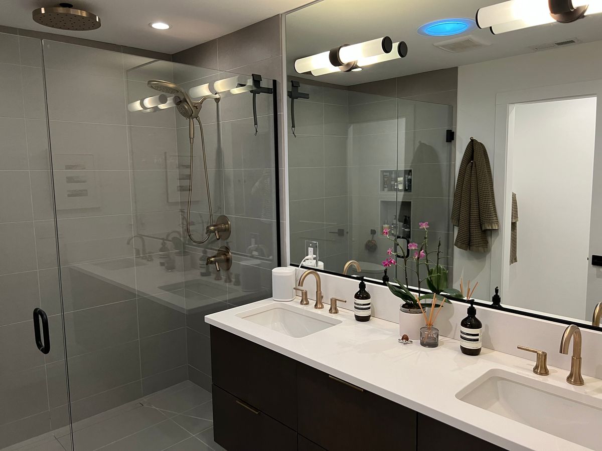 New bathroom with double vanity, large-format grey tile and glass shower