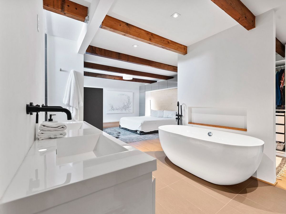 Remodeled bath with freestanding tub, exposed beam and matte black fixtures