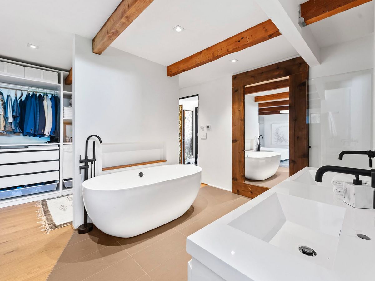 Second bath: freestanding tub, walk-in closet beyond, exposed beams overhead