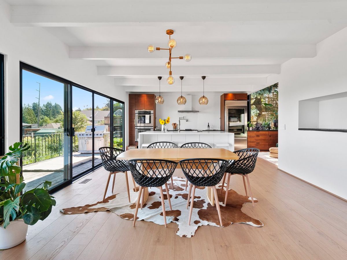 Open kitchen and dining under exposed beams, planned around a new sliding wall to the deck